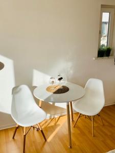 ホンブルクにあるAn der Uniklinik, Apartment mit eigener Küche und renoviertem Badezimmer, Zentrale Lageの白いテーブルと白い椅子2脚