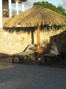 a table and two chairs under a straw umbrella at villa du vieux moulin de gissac in Sainte-Anne