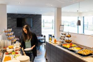 a woman holding a plate in front of a buffet at Hotel DuDa Langenbruck 3-Sterne-Superior-Hotel an der A9 zwischen Ingolstadt und München in Langenbruck