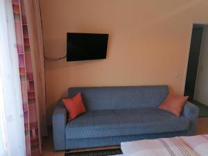 a living room with a blue couch and a tv on the wall at Ledererhof in Oberlienz