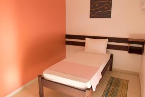 Cama pequeña en habitación con paredes de color naranja en Pousada Terceiro Espaço en Guaibim