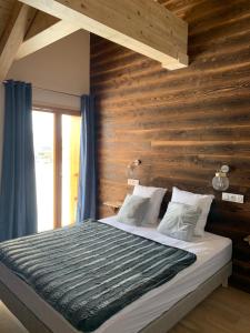 a bed in a room with a wooden wall at SKI LODGE in La Toussuire
