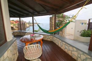 a porch with a hammock and a table and chairs at Catcha Falling Star in Negril