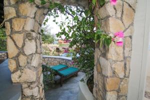 a stone wall with a bench and pink flowers at Catcha Falling Star in Negril