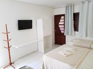um quarto branco com uma cama e uma televisão em Pousada Praia da Barra na Barra de São Miguel