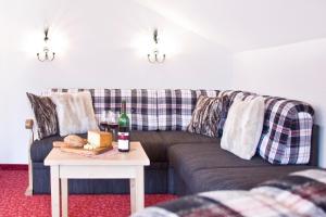 a living room with a couch and a table with a bottle of wine at Ferienwohnungen Gästehaus Schraudolf in Oberstdorf