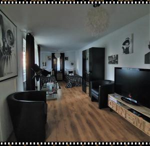 ein Wohnzimmer mit Flachbildfernseher und schwarzen Sesseln in der Unterkunft Kolev Apartments in Kelsterbach