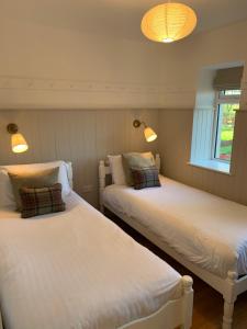 two beds in a room with lights on the wall at The Old Dairy at Walkmill Farm in Bushmills