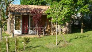 a small house with a porch and a table in the yard at CAMPING LES GRAVES in Saint-Pierre-Lafeuille