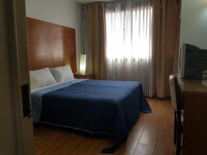 1 dormitorio con 1 cama con manta azul y ventana en Al Porteño en Buenos Aires
