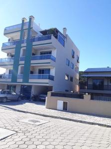 ein großes weißes Gebäude mit davor geparkten Autos in der Unterkunft Residencial helena cobertura in Bombinhas