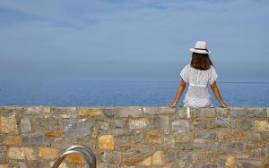 Vasia Resort & Spa في سيسي: امرأة تجلس على الحائط وتطل على المحيط