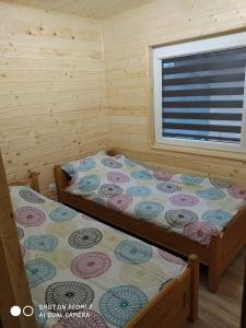 a bedroom with two beds and a window at Domki na lipowej in Pastwiska