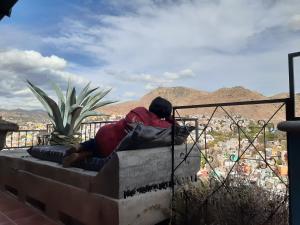 un hombre sentado en una cornisa con vistas a una ciudad en Hostal Casa de Dante, en Guanajuato