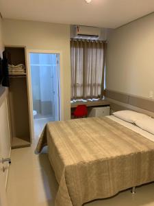 a bedroom with a bed and a door to a bathroom at Hotel Catarina in São Miguel dʼOeste