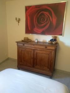 a painting on a wall above a wooden dresser with a bed at La Dame de Messignac in Ternand
