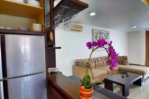 a living room with a couch and a table with a flower at Sunset Residence and Condotel in Legian