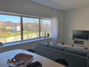 sala de estar con sofá, TV y ventanas en Ninon- Premium Trindade by Porto City Hosts en Oporto