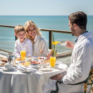 una familia sentada en una mesa comiendo comida en Hotel Costa Galana en Mar del Plata