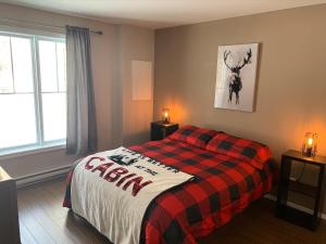 1 dormitorio con 1 cama con manta a cuadros en Condo Mont-Edouard en LʼAnse-Saint-Jean