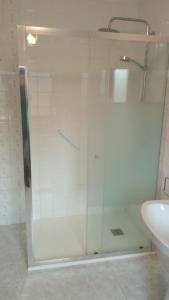 prysznic ze szklanymi drzwiami obok umywalki w obiekcie Casa la Pontiga w mieście Las Rozas