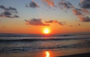 einen Sonnenuntergang am Strand mit dem Meer in der Unterkunft Sunset Residence and Condotel in Legian