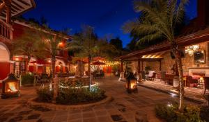 a courtyard with tables and chairs and palm trees at night at Hotel Boutique Casa Colorada in Pátzcuaro