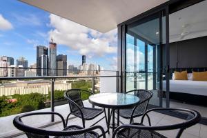 a balcony with a table and chairs and a view of the city at Hope Street Apartments by CLLIX in Brisbane