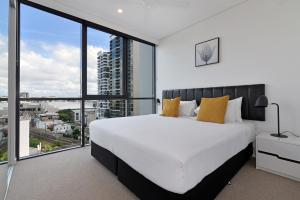 a bedroom with a large white bed and large windows at Hope Street Apartments by CLLIX in Brisbane