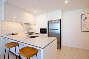 a kitchen with white cabinets and a counter and stools at Hope Street Apartments by CLLIX in Brisbane