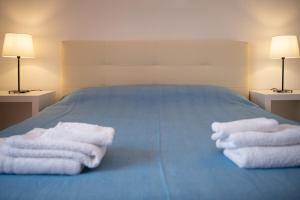 two towels on a blue bed with two lamps at House Santa Caterina in Rome