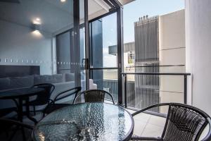 a glass table and chairs in a living room at Hope Street Apartments by CLLIX in Brisbane