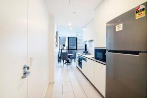 a kitchen with a stainless steel refrigerator and a table at Hope Street Apartments by CLLIX in Brisbane