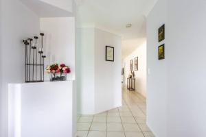 un pasillo con paredes blancas y flores en jarrones en Executive and Family Home Large - Flinders View 24, en Ipswich