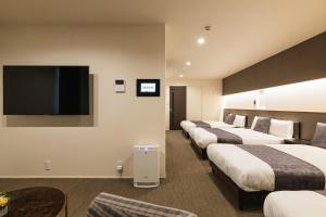 a hotel room with four beds and a flat screen tv at GRAND BASE Nagasaki City in Nagasaki