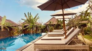 a row of lounge chairs with an umbrella next to a swimming pool at Gedong Nusa Huts in Nusa Lembongan