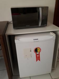 a microwave sitting on top of a white refrigerator at Acquaville Flat in Caldas Novas