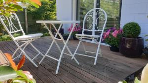 2 weiße Stühle und ein Tisch auf einer Veranda in der Unterkunft Dragonflycottagebnb in Grovetown