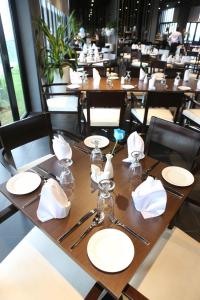 una mesa de madera con platos blancos y servilletas. en e.City Hotel@OneCity, en Subang Jaya
