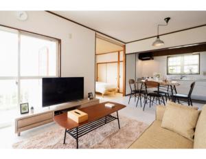 ein Wohnzimmer mit einem Sofa und einem TV in der Unterkunft Anjin Stay Awaji - Self Check-In Only in Akashi