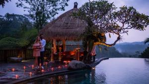 una coppia in piedi di fronte a una piscina in un resort di Adiwana Dara Ayu Villas a Payangan