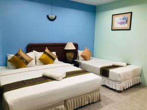 2 Betten in einem Zimmer mit blauen Wänden in der Unterkunft A.K. Terrace Hotel in Sara Buri
