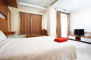 - une chambre avec un grand lit blanc et une télévision dans l'établissement Kamarku Apartment, à Cimindi-hilir