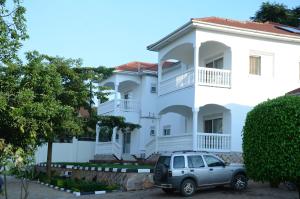 samochód zaparkowany przed białym domem w obiekcie Muyenga Luxury Vacation Home w mieście Kampala