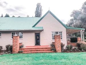 a white house with a green roof at Pennygum Country Cottages in Underberg