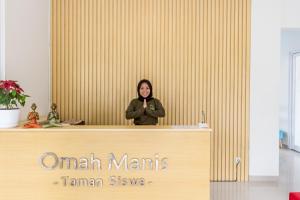 a woman standing behind a counter in a room at Omah Manis in Yogyakarta