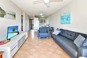 a living room with a couch and a tv at Warroo Apartments in Alexandra Headland