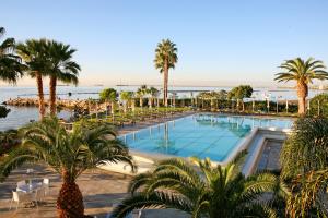 a pool with palm trees and chairs and the ocean at Crowne Plaza Limassol by IHG in Limassol