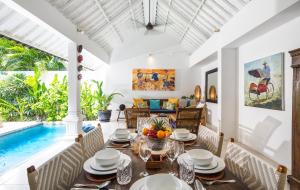 a dining room with a table and a swimming pool at Villa Atma in Seminyak