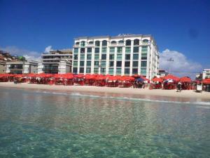 un edificio con sombrillas rojas en una playa con el océano en Loft Prainha, en Arraial do Cabo